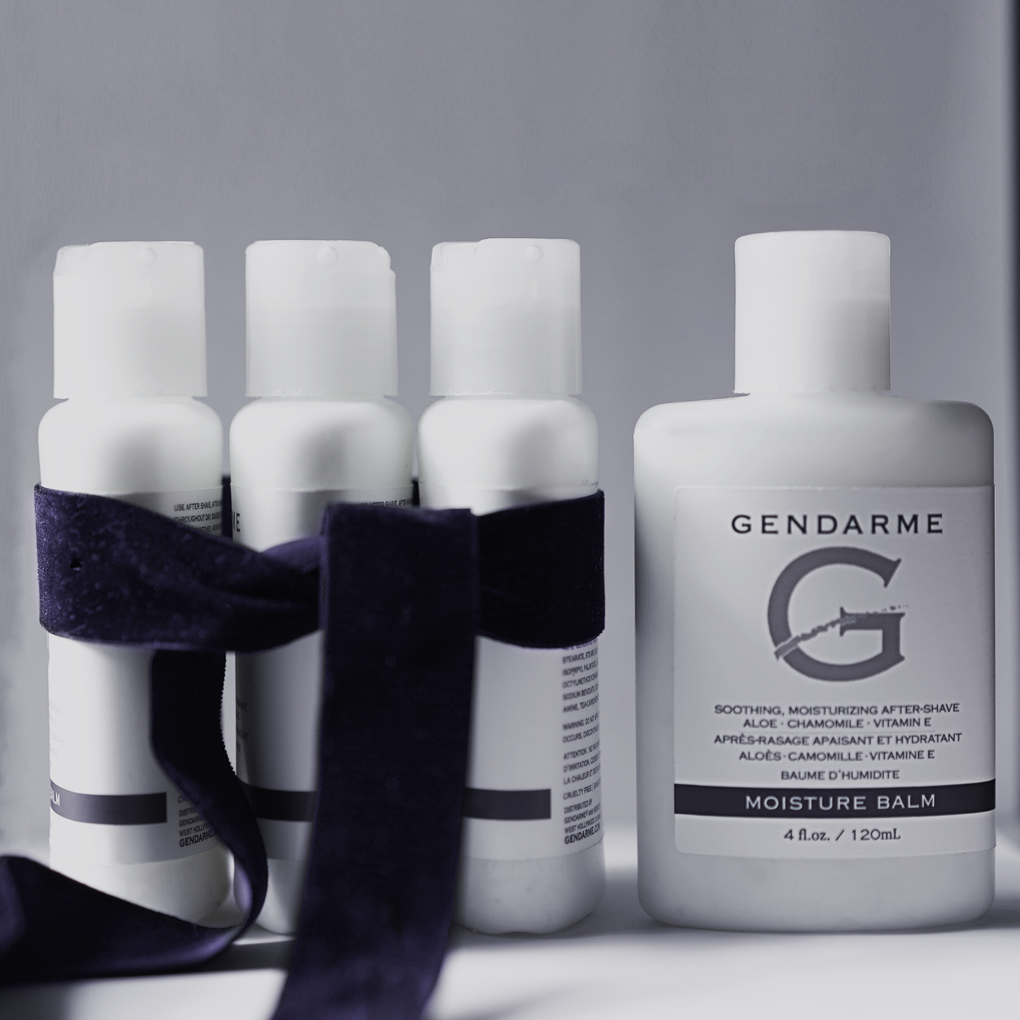 A decorative banner featuring Gendarme skincare products with a blue ribbon around three bottles on a gray background