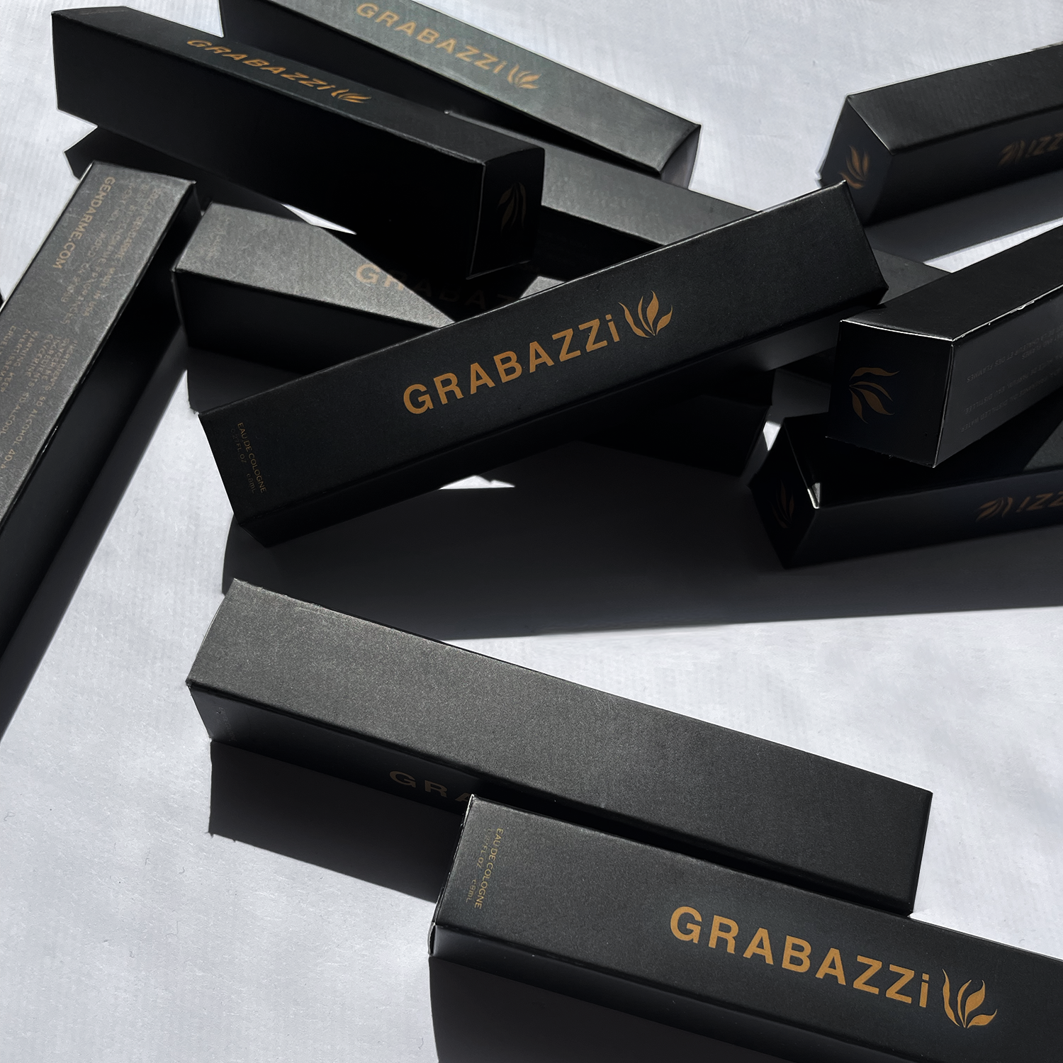 Decorative Image of Grabazzi Travel spray. Multiple black  boxes with Gold Grabazi logo on white background 
