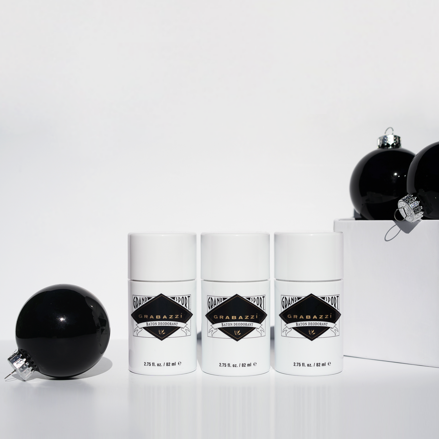 Three white grabazzi bottles with black labels on a white background with black ornaments.