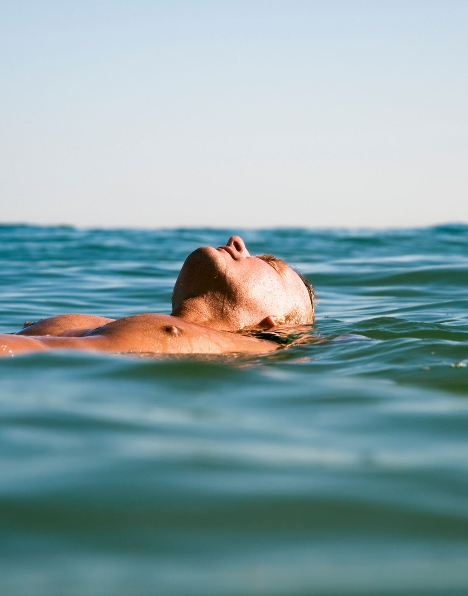 decorative image of man floating  in ocean water with eyes closed. 